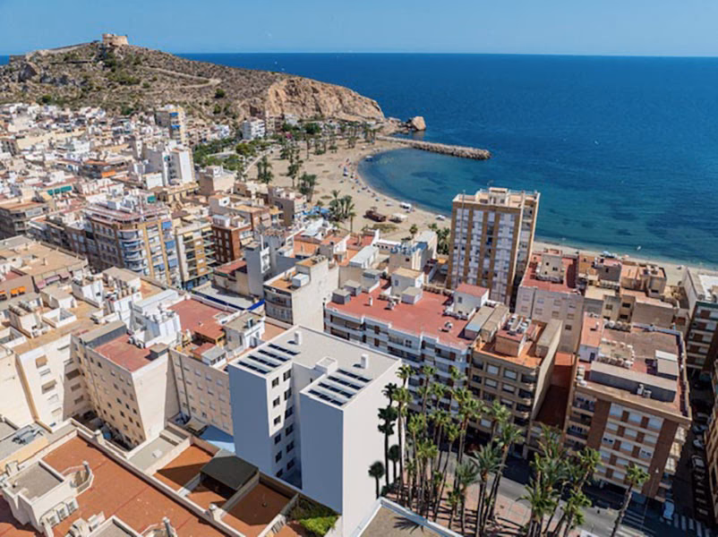 El edificio en el centro, con la playa y el cerro del castillo detrás