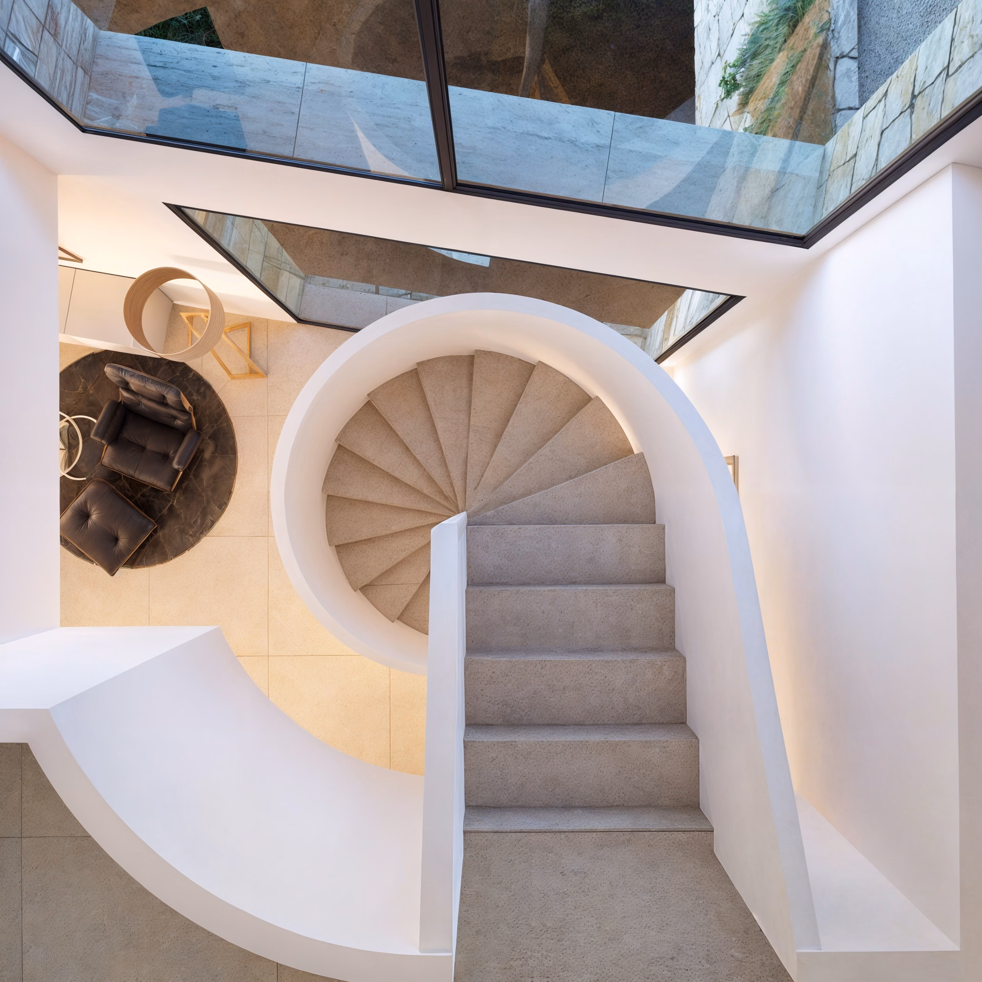 Weiße Wendeltreppe von oben gesehen, durch ein Oberlicht erhellt