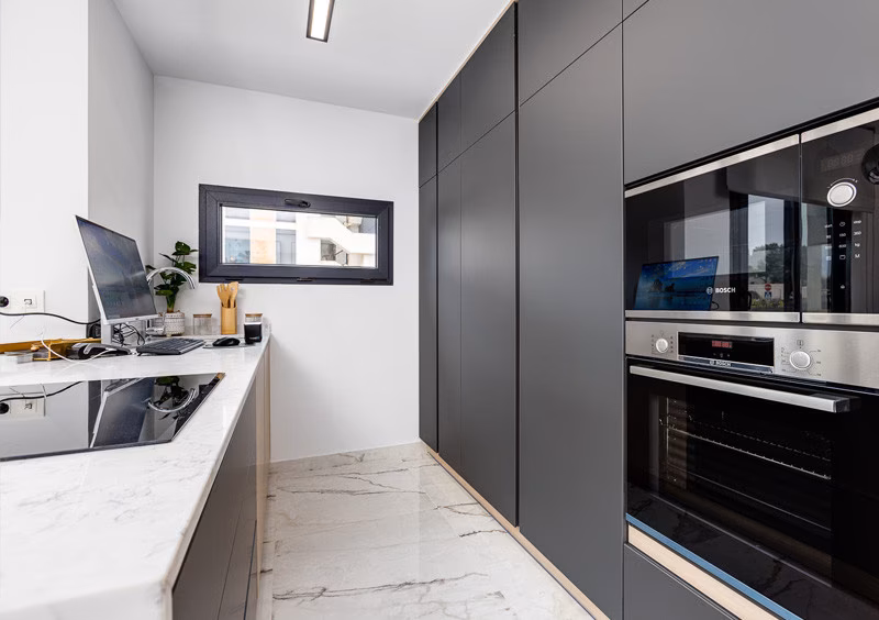 Kitchen with dark tall units and built-in oven in the La Hoya show apartment