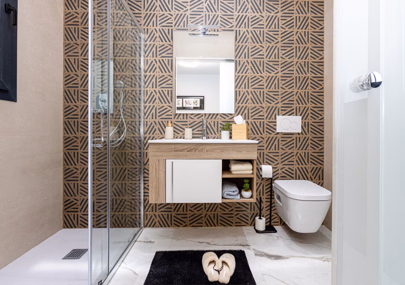 Bathroom with patterned tiles and glass shower screen in the La Hoya show apartment