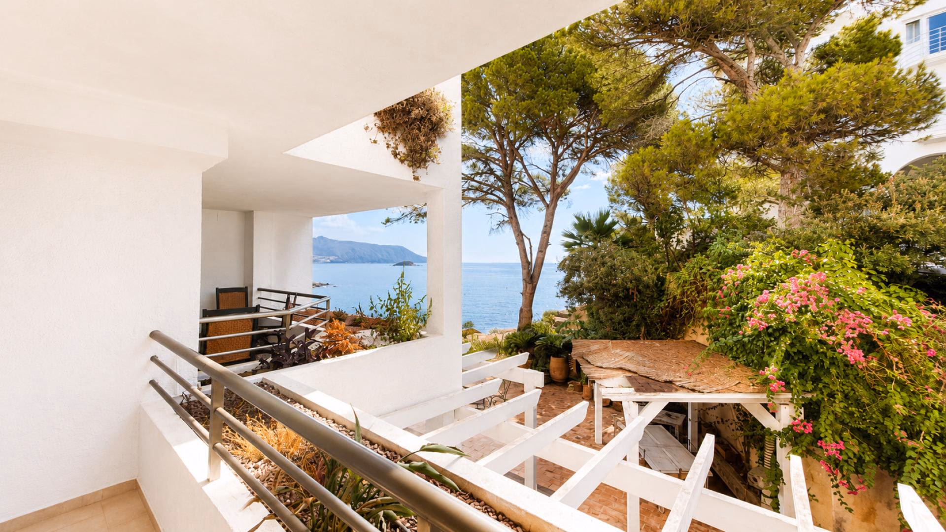 Balkon mit Blick auf die Gartenterrasse und das Meer durch die Pinien