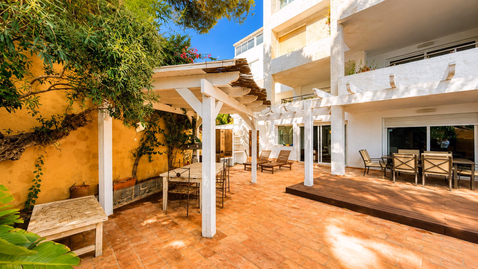 Terrasse unter einer Holzpergola neben dem Haus mit Glasschiebefront