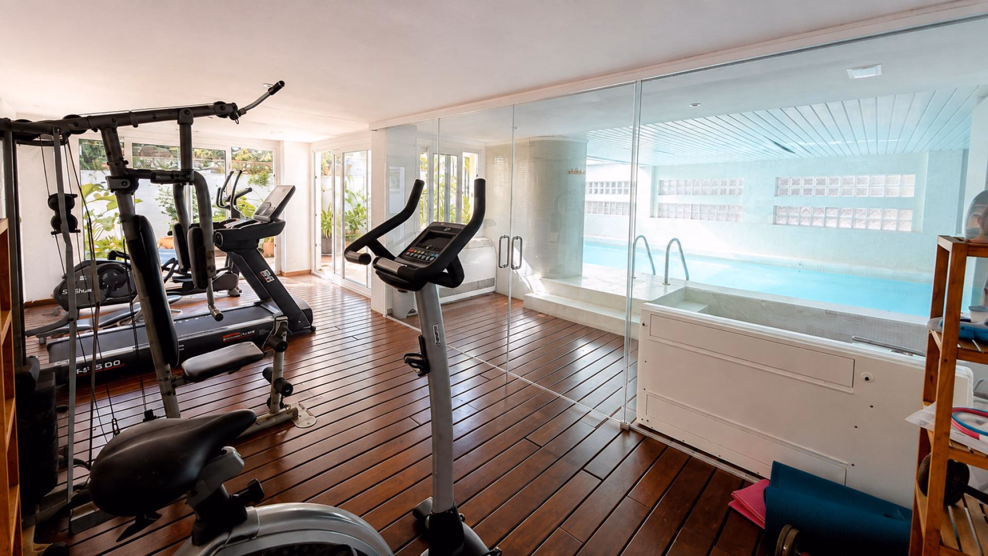 Fitnessraum für Bewohner mit Trainingsgeräten neben dem Hallenbad