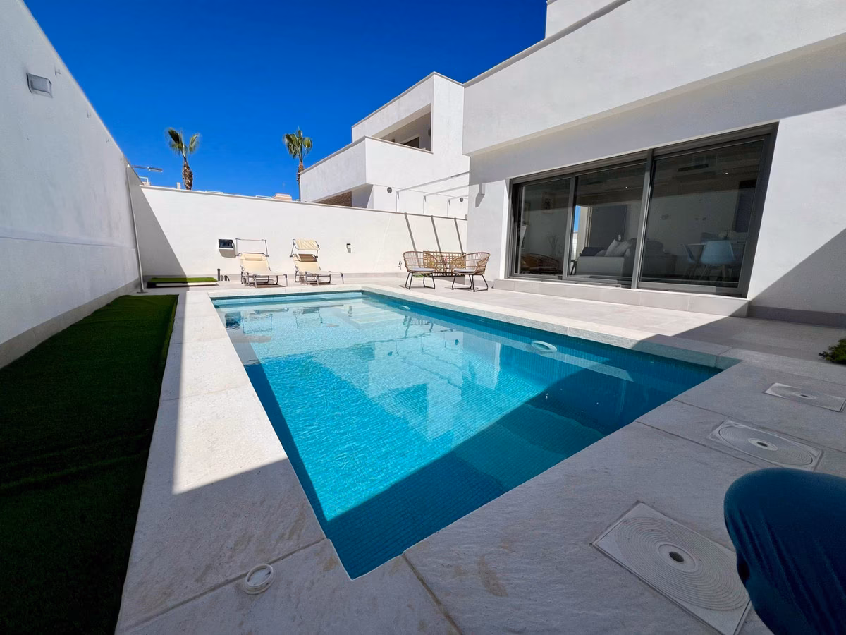 Private pool running along the villa with artificial lawn