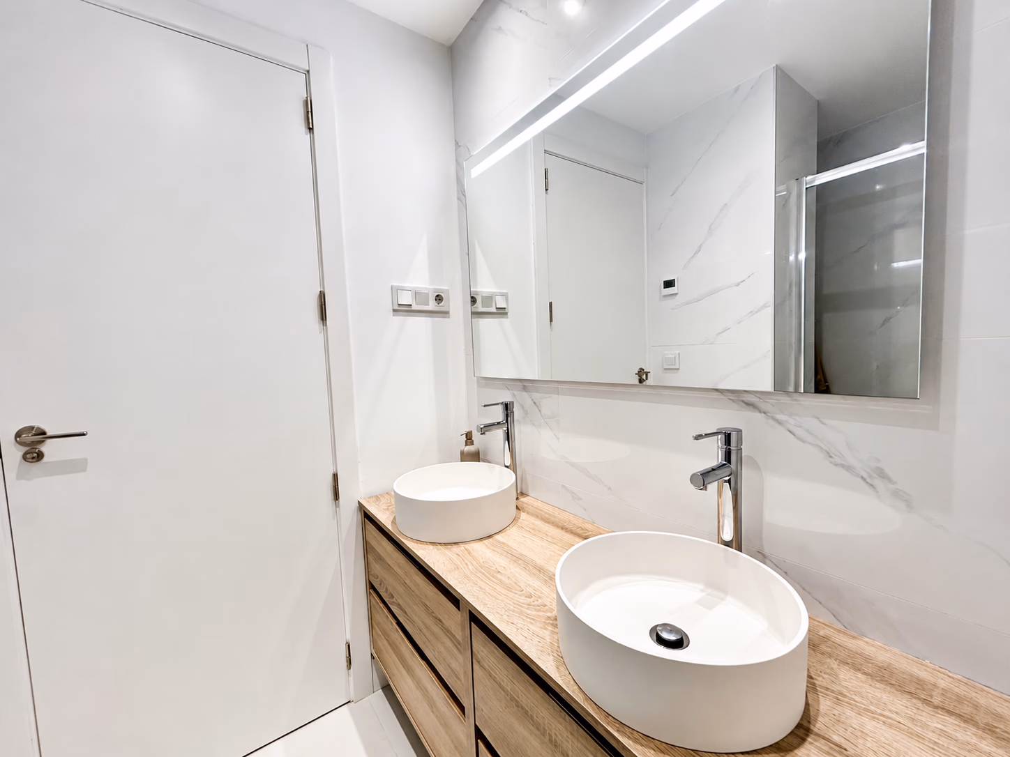 Ensuite badkamer met dubbele wastafels en marmerlook tegels bij Lomas 2