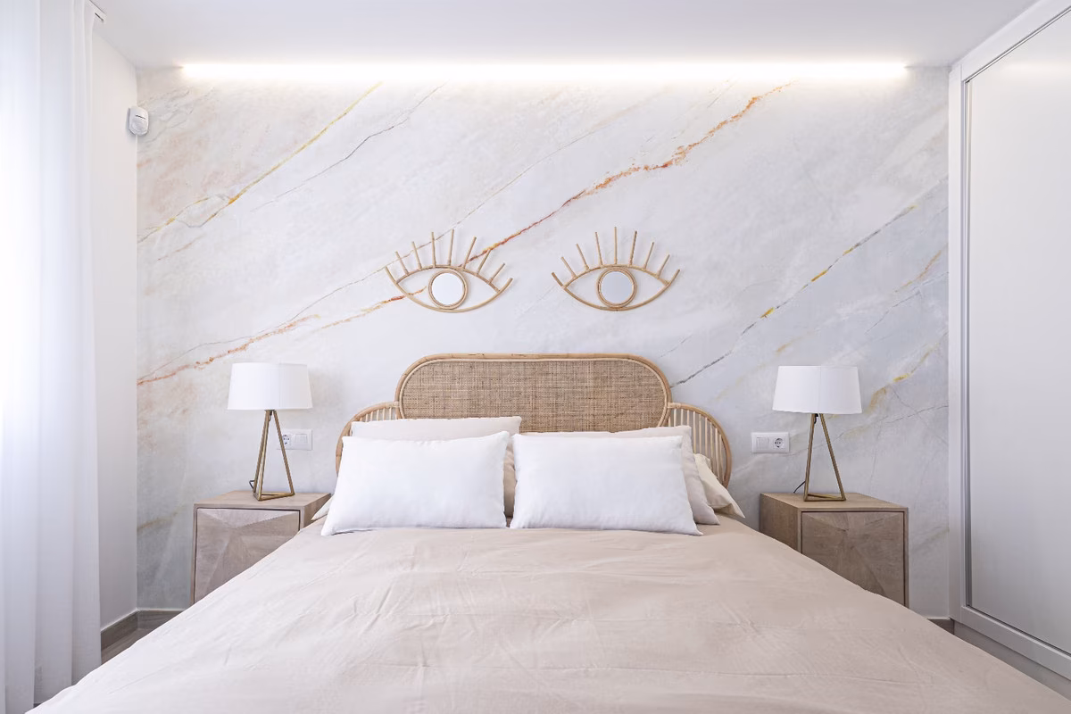 Schlafzimmer mit Wand in Marmoroptik und Rattan-Kopfteil