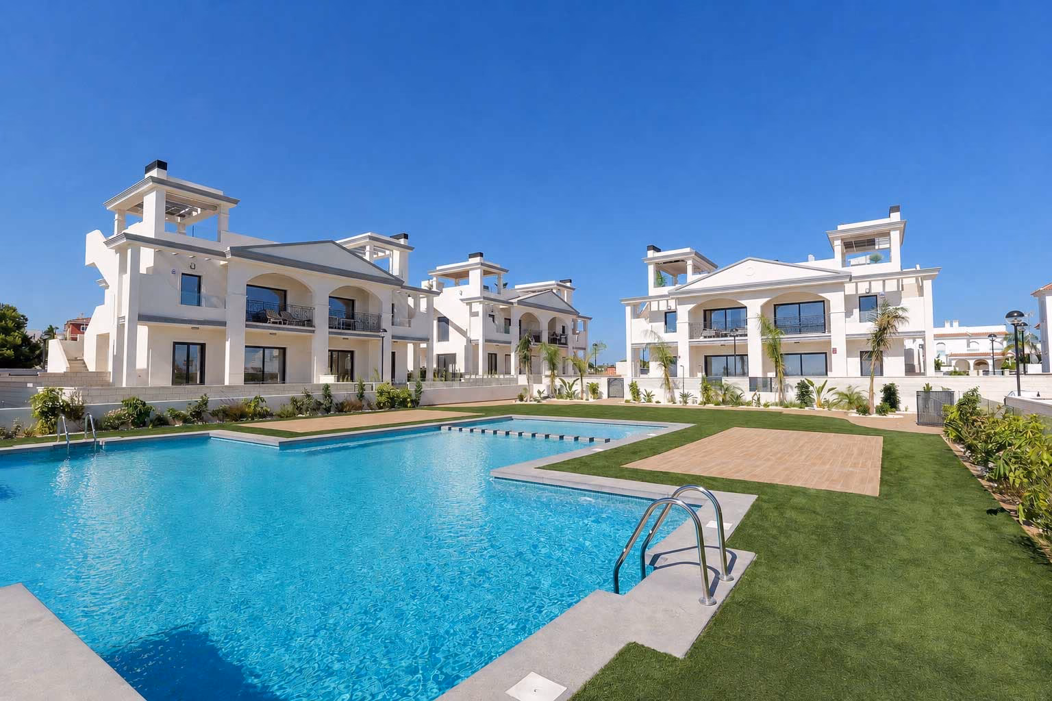 Piscine commune et plage de piscine devant des immeubles blancs à un étage
