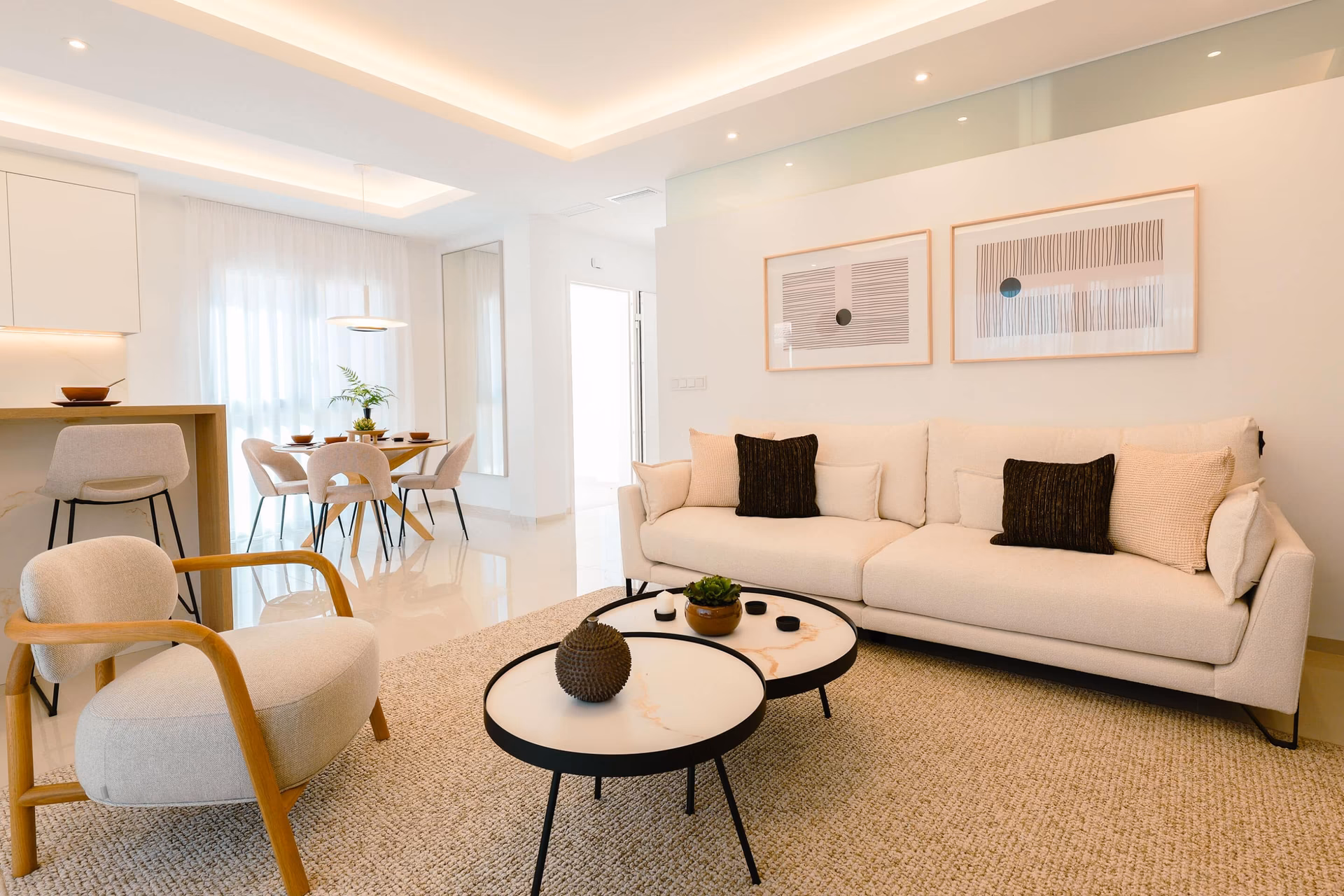 Appartement témoin : séjour avec canapé, fauteuils et table de salle à manger