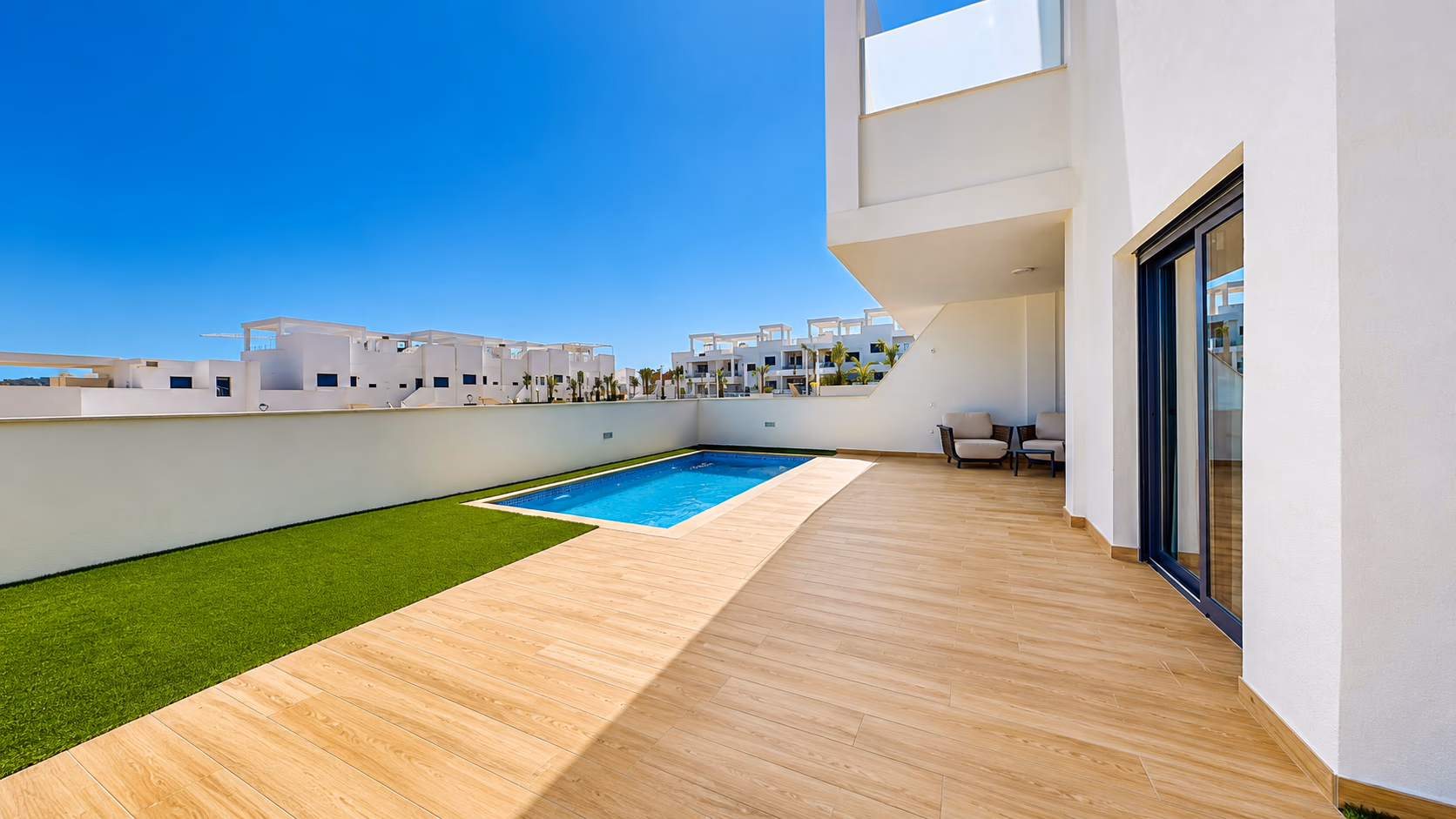 Außenansicht des Eckbungalows mit Pool und Rasenfläche