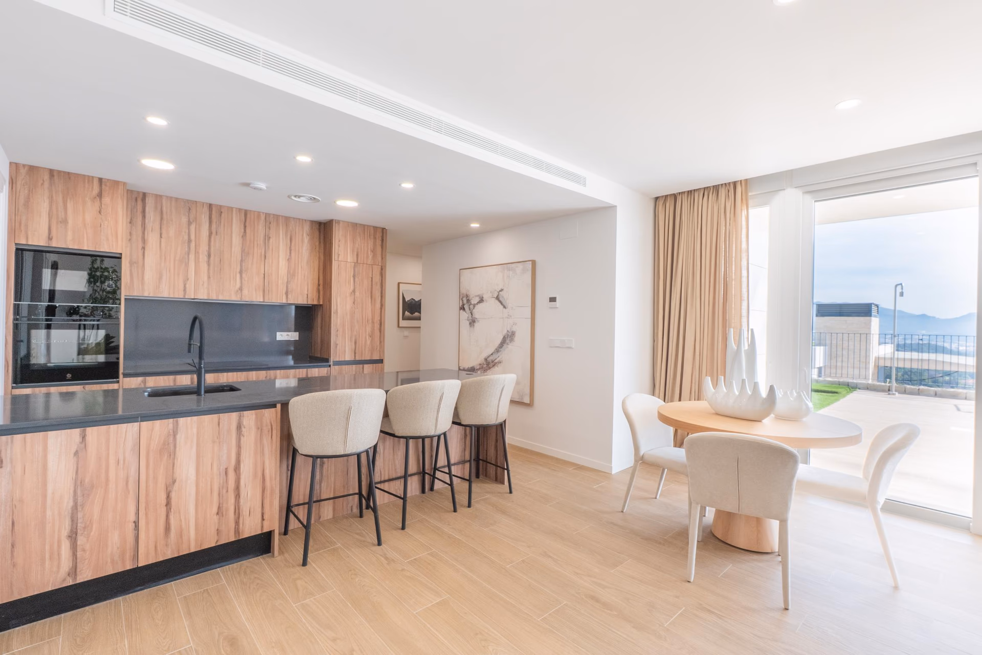 Open-plan kitchen with island and dining area opening onto the terrace of the show villa