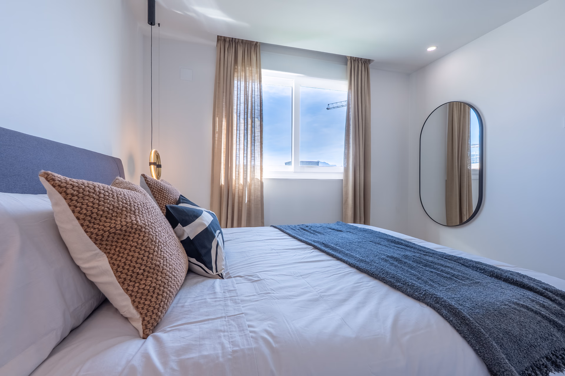 Bed detail with patterned cushions and oval mirror