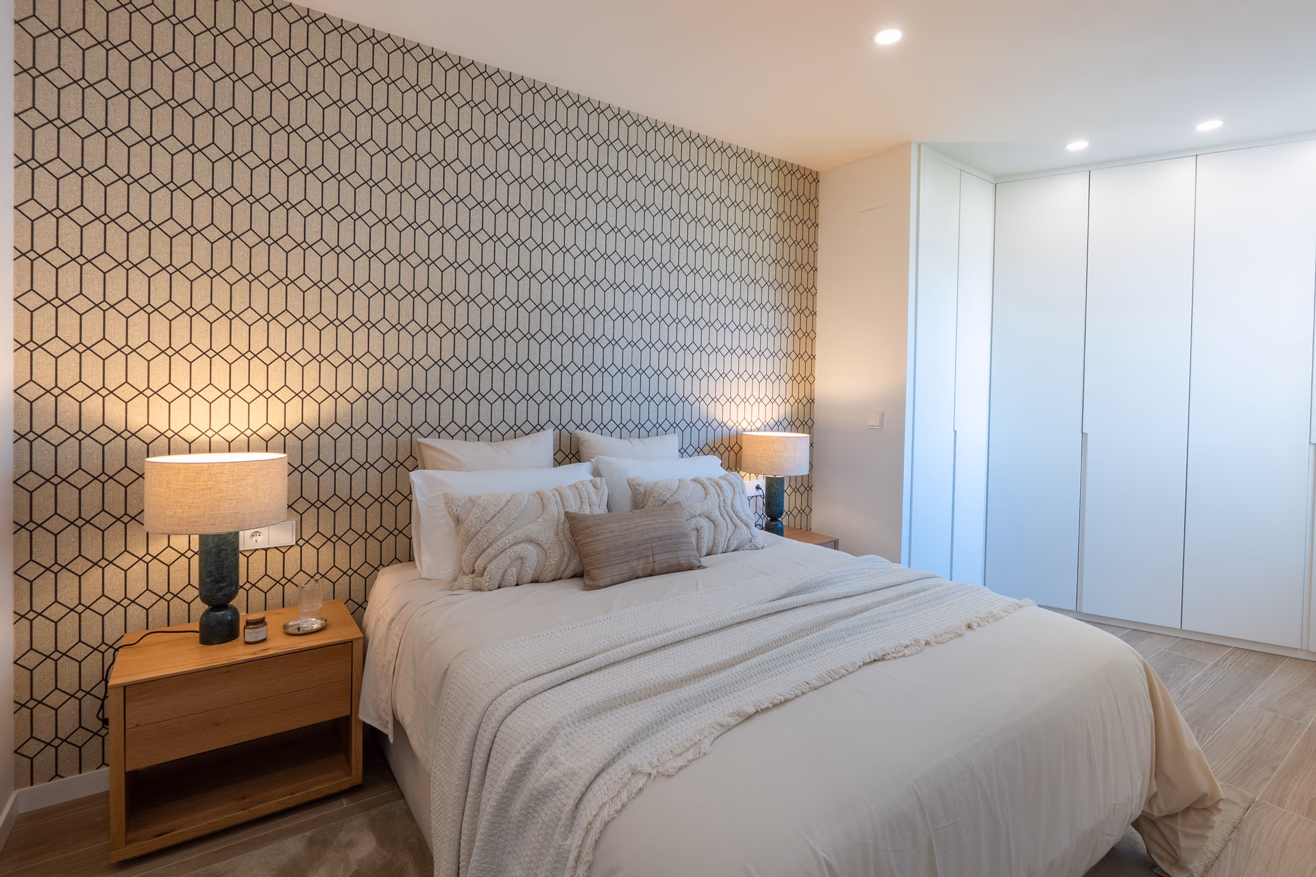Master bedroom with geometric wallpaper and fitted wardrobes