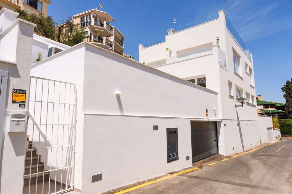 Weiße Fassade und Garagentor von Monte Sancha 28 an einer Hangstraße in Málaga Este