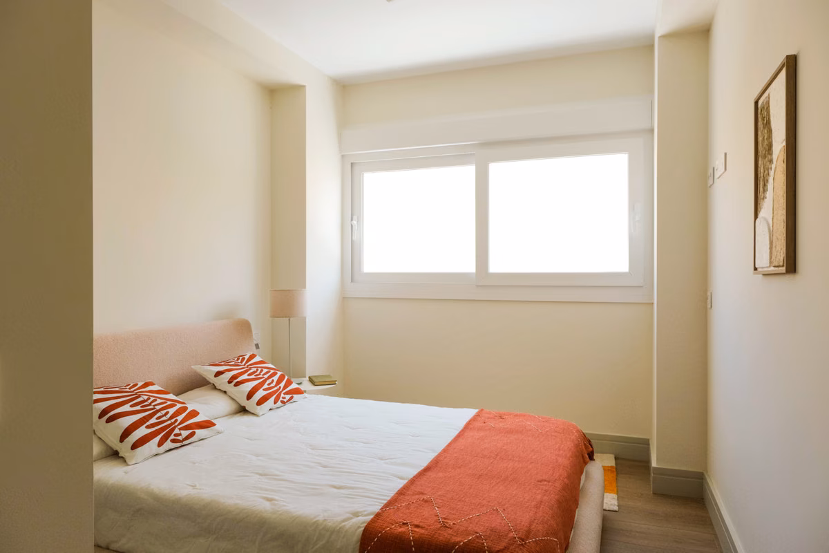 Schlafzimmer mit rosa Kopfteil und orangefarbener Decke in Monte Sancha 28