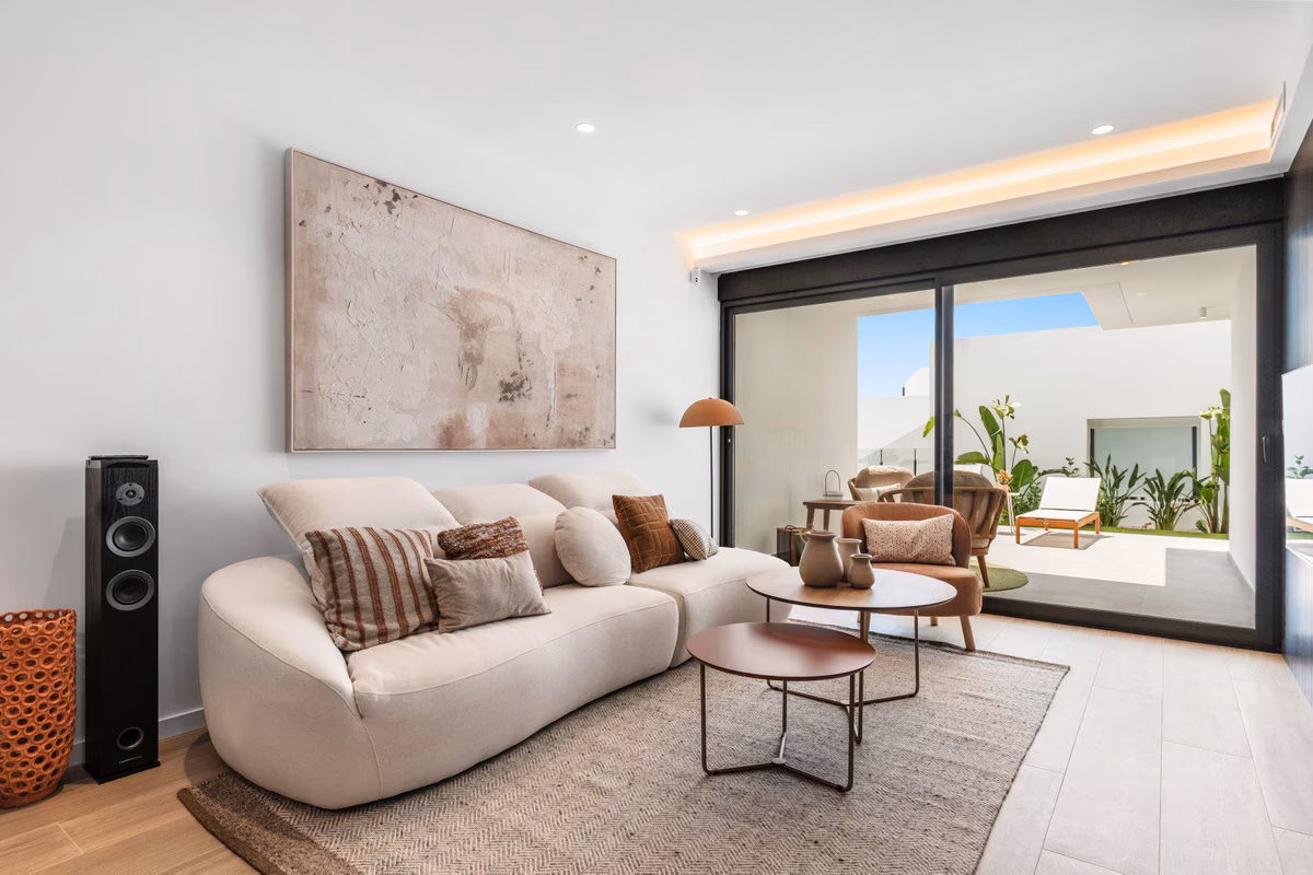 Wohnzimmer mit geschwungenem Sofa und Glasschiebetüren zur Terrasse