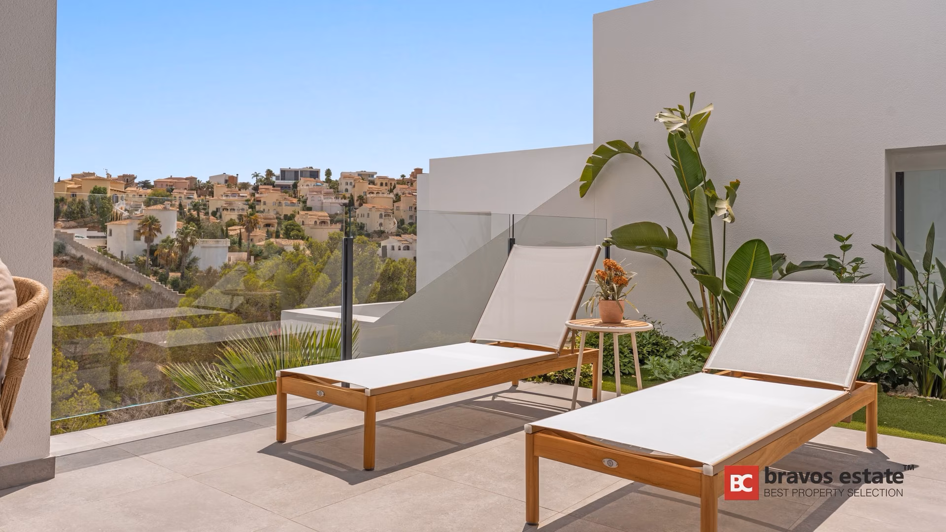 Terrasse mit zwei Holzliegen und einer Bananenpflanze über dem Hang