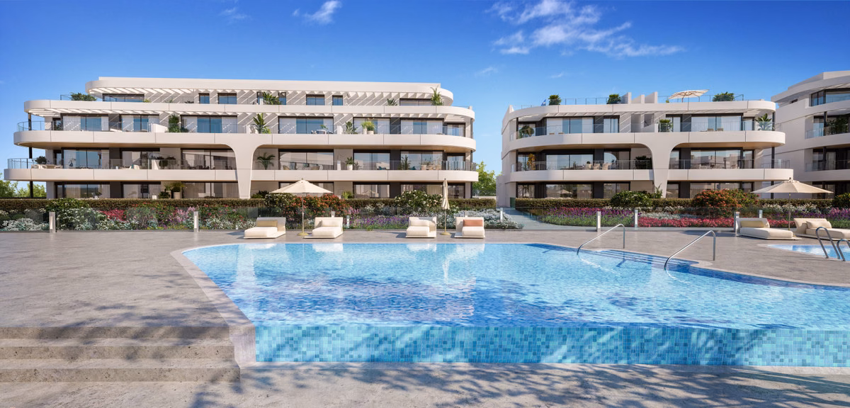 Piscina comunitaria con césped y palmeras entre los edificios de Naya Residences