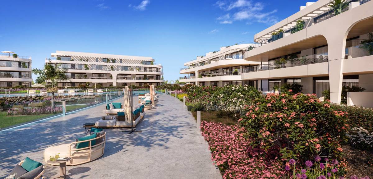 Paseo junto a la piscina con tumbonas y plantación florida en Naya Residences