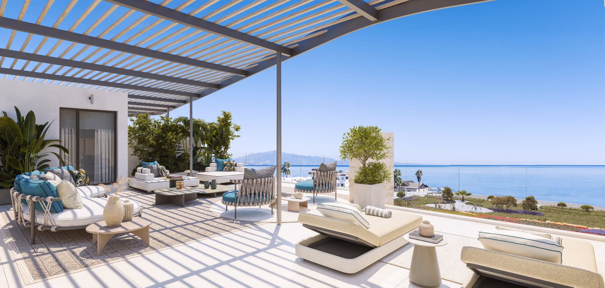 Terrace under a slatted pergola with loungers and sea views