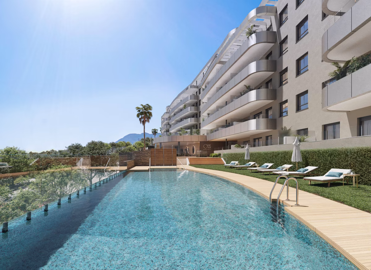 Gemeinschaftspool mit Überlaufkante, Rasen und Sonnenliegen bei One Oak, Torremolinos
