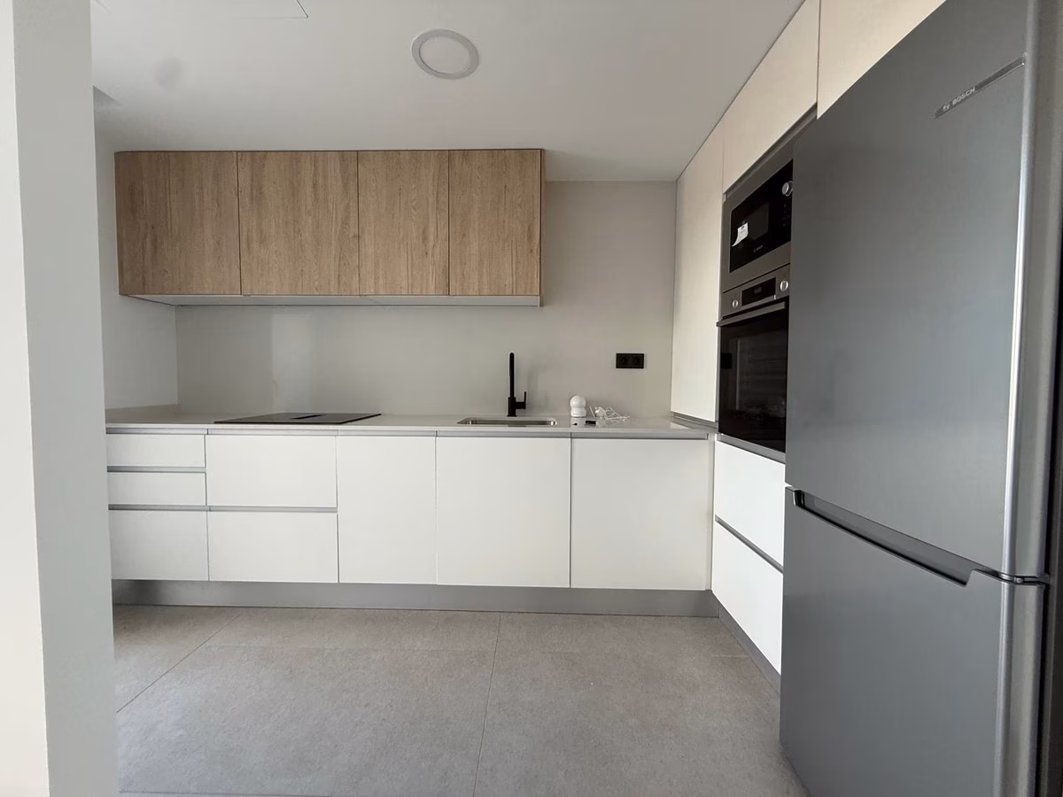 Küche in Weiß und Holz mit Einbaubackofen und Kühlschrank in einer Wohnung von Panoramar