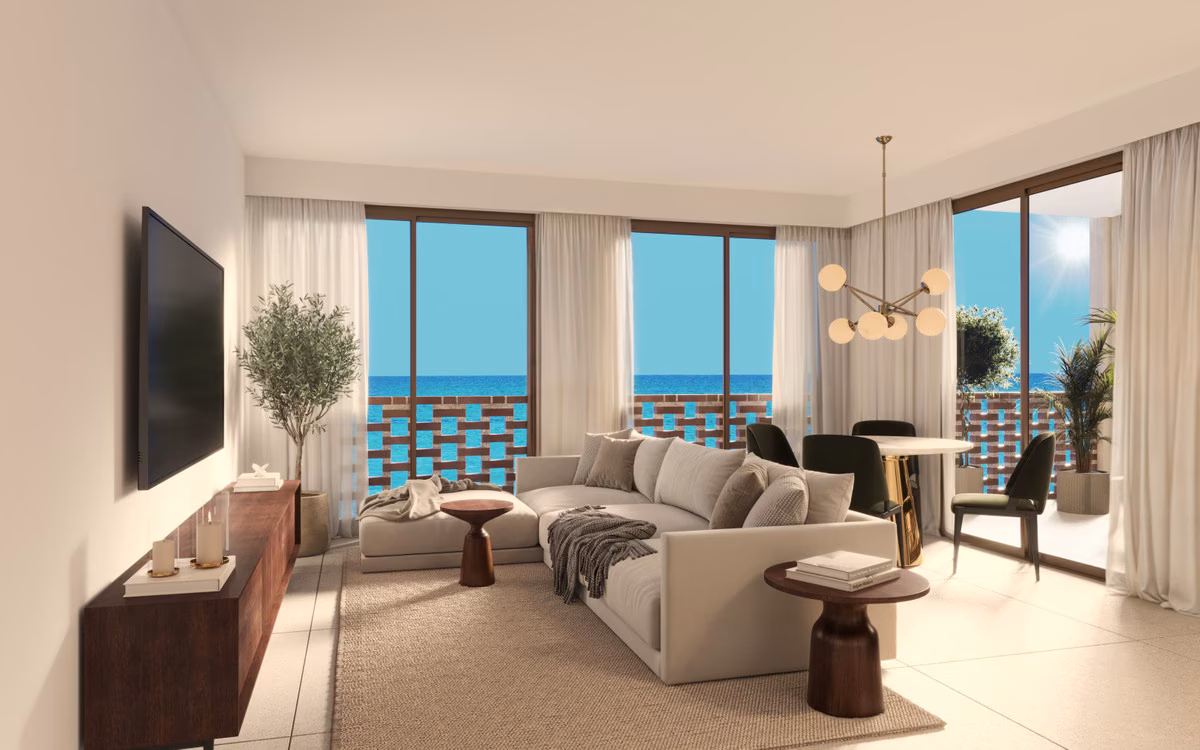 Wohnzimmer mit Sofa, Esstisch und Glastüren zur Terrasse mit Meerblick