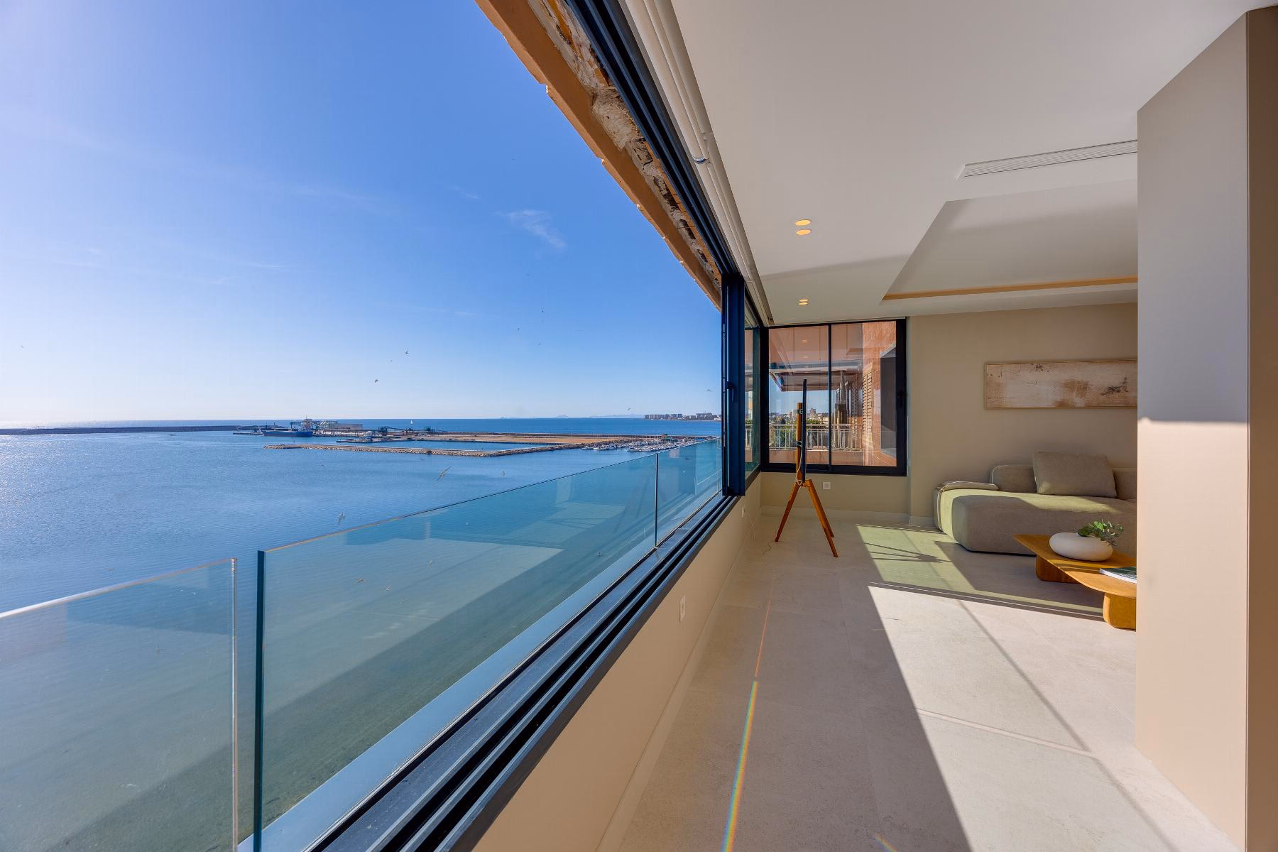 Glazed terrace running along the apartment with a glass balustrade above the sea