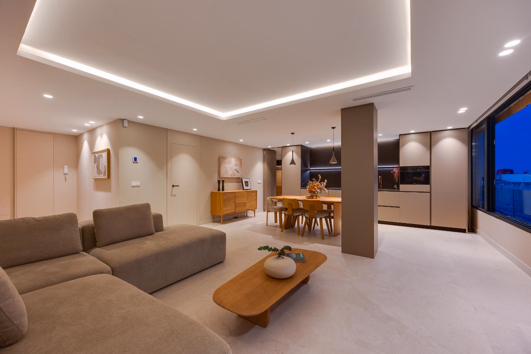 Living room with recessed ceiling lighting, sofa and the kitchen behind