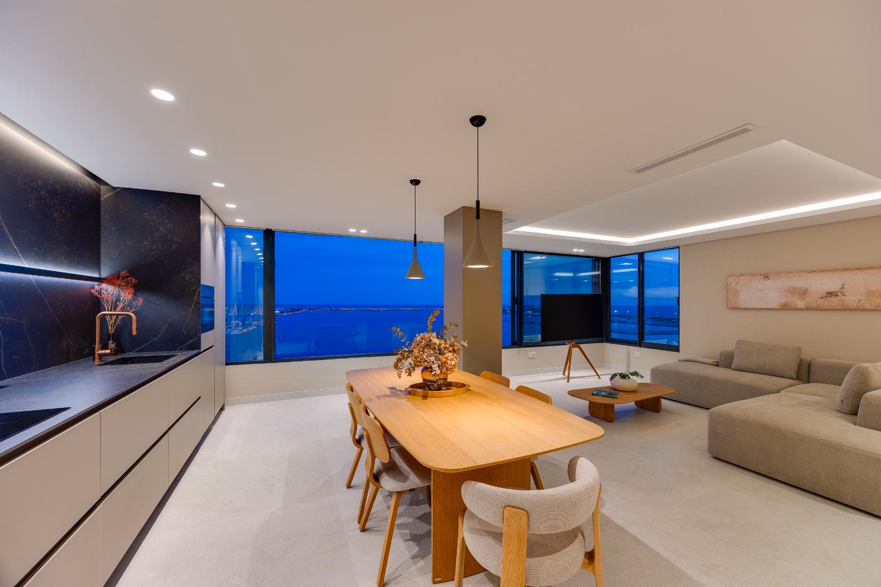 Kitchen, dining table and living room in one space with windows to the sea