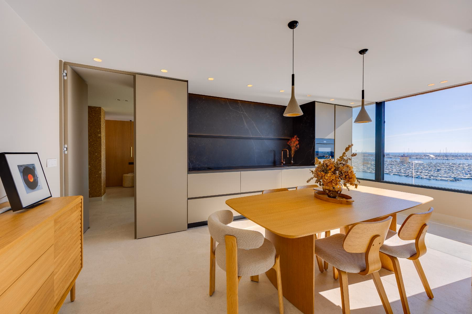 Dining table with wooden chairs in front of the kitchen and a sliding door