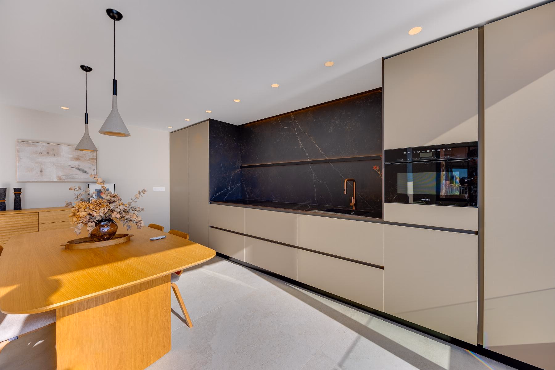 Wooden dining table in front of the kitchen units