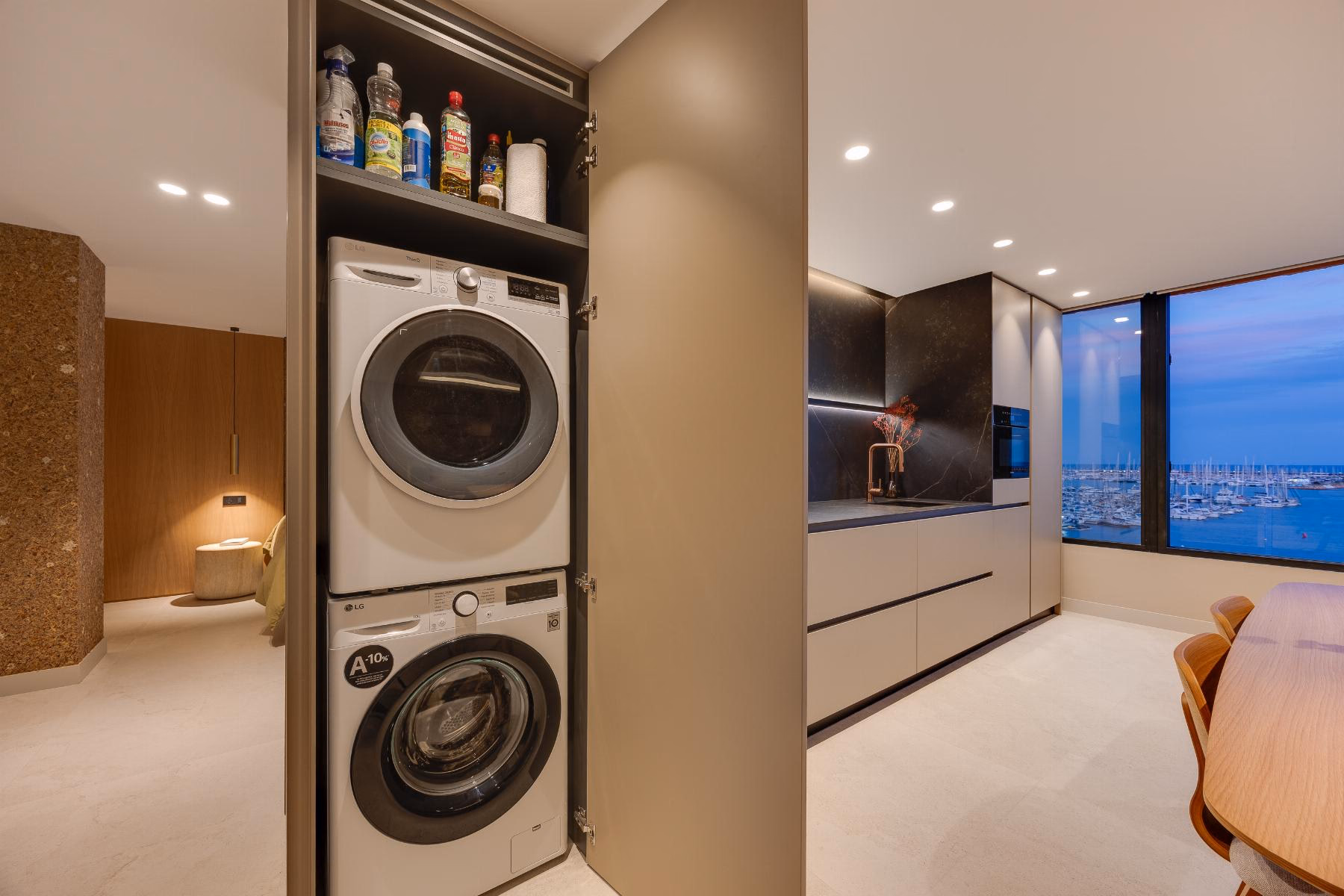 Laundry cupboard with stacked washing machine and dryer next to the kitchen