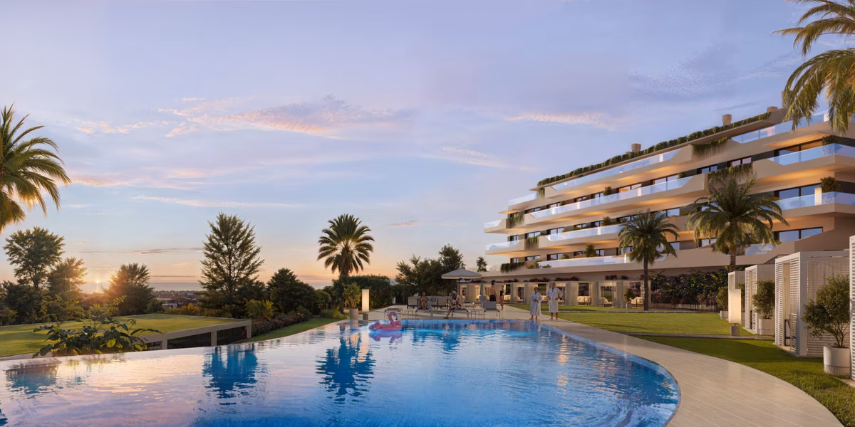 Piscina de borde curvo junto al césped y el edificio de terrazas al atardecer