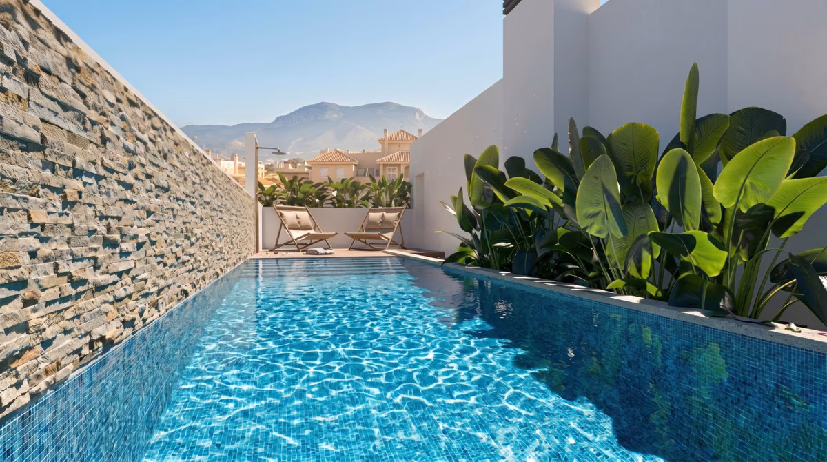 Rooftop swimming pool beside a stone-clad wall with tropical plants and mountain views