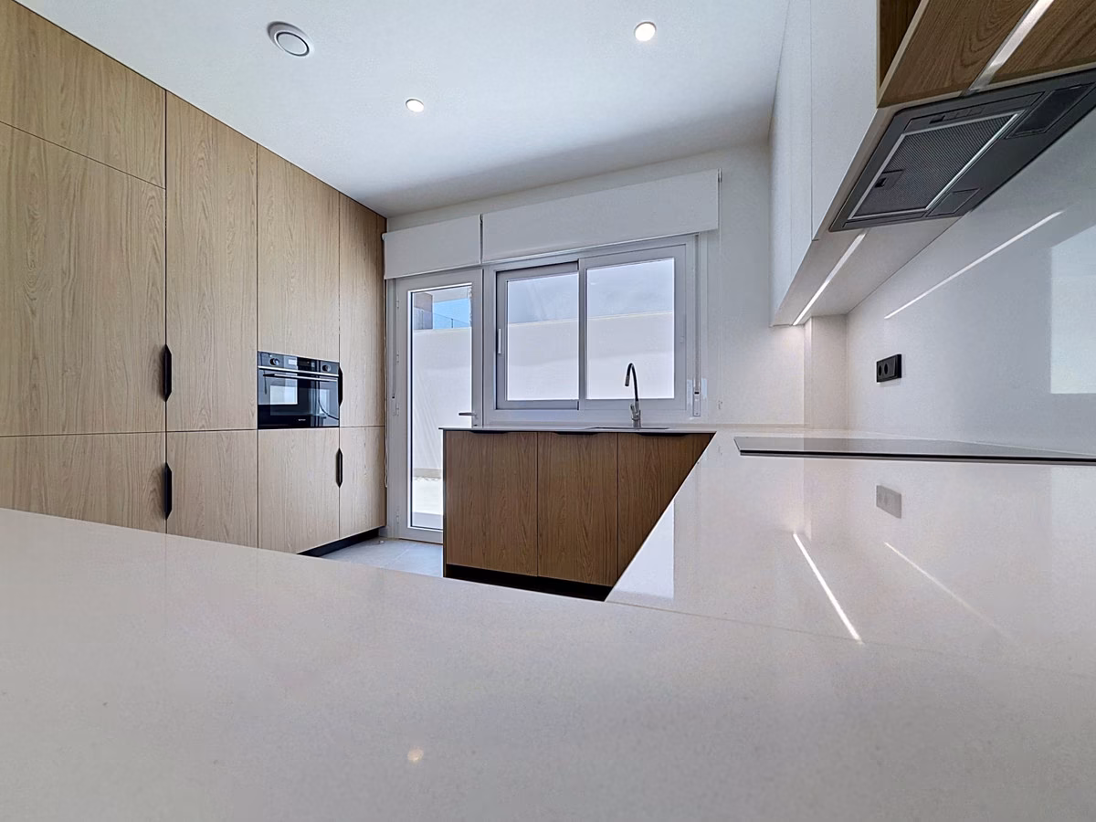 Tall oak units with built-in oven next to the white kitchen counter