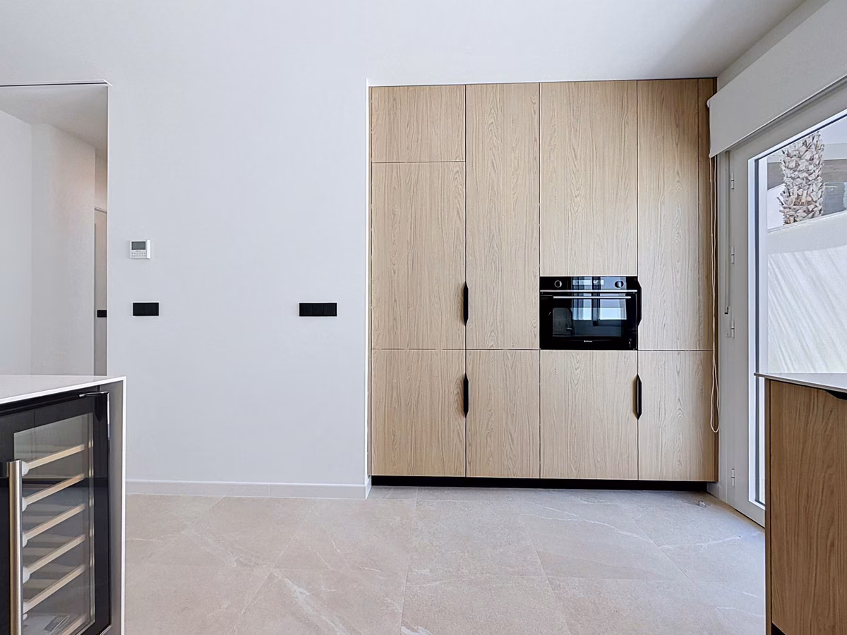 Wall of tall oak cabinets with built-in oven, wine cooler in front