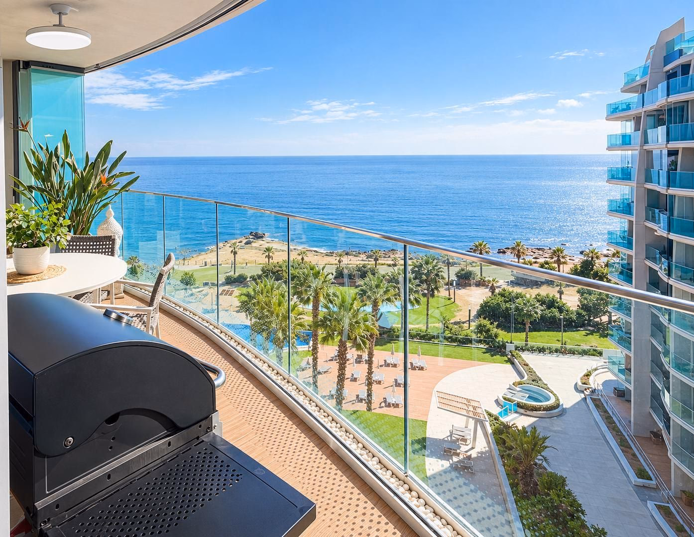 Terraza con barandilla de cristal sobre los jardines y piscinas de Sea Senses y el mar al fondo