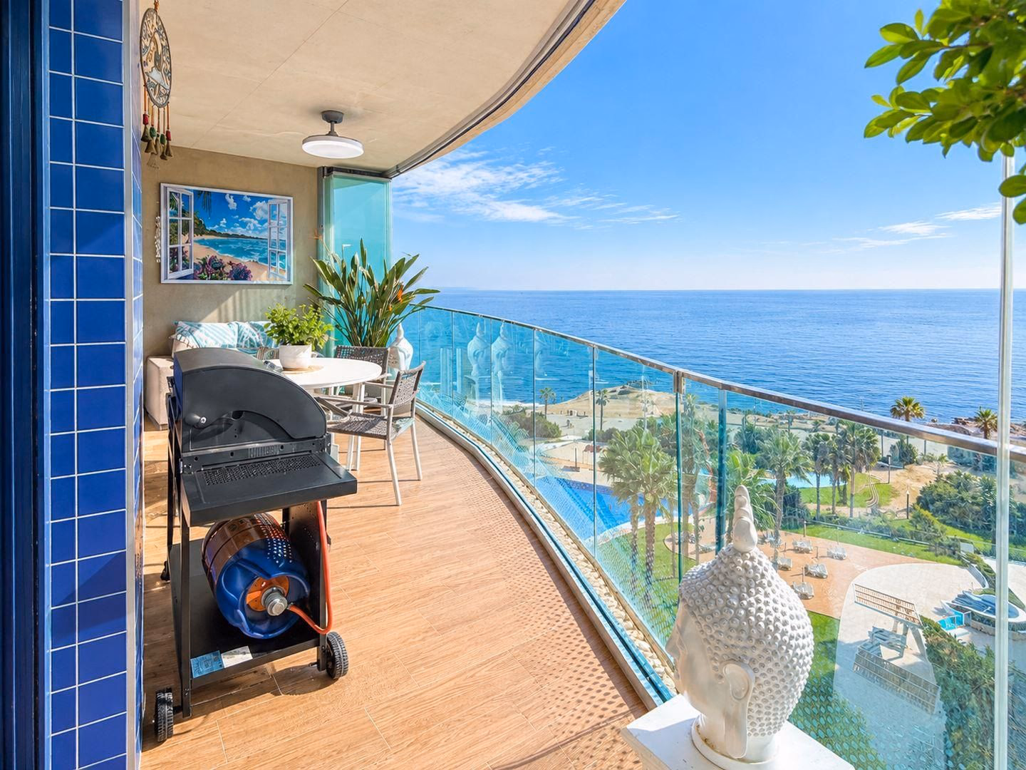 Terraza con barbacoa, plantas y barandilla de cristal curva sobre la costa de Punta Prima