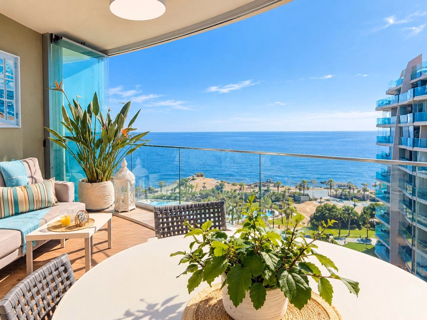 Rincón de estar en la terraza acristalada con cortinas de cristal plegables y el mar abierto