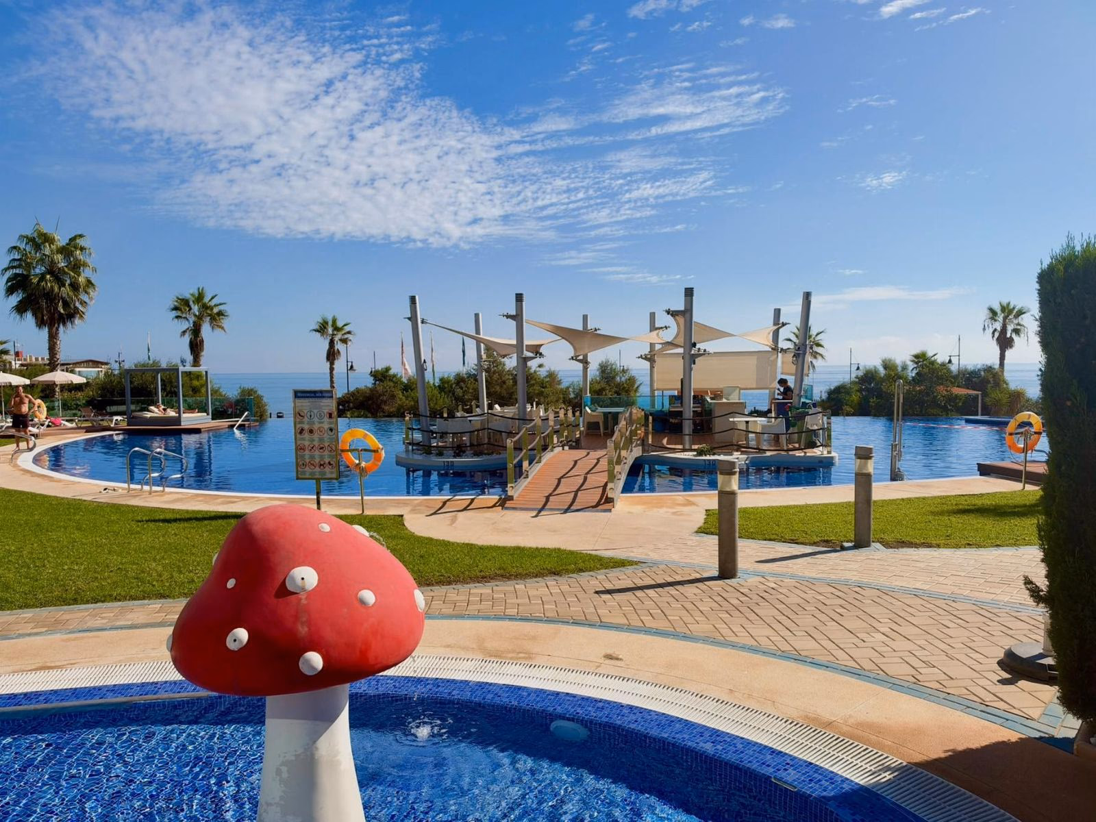 Piscina infinita de Sea Senses con zona de chapoteo infantil, jardines y el mar en el horizonte