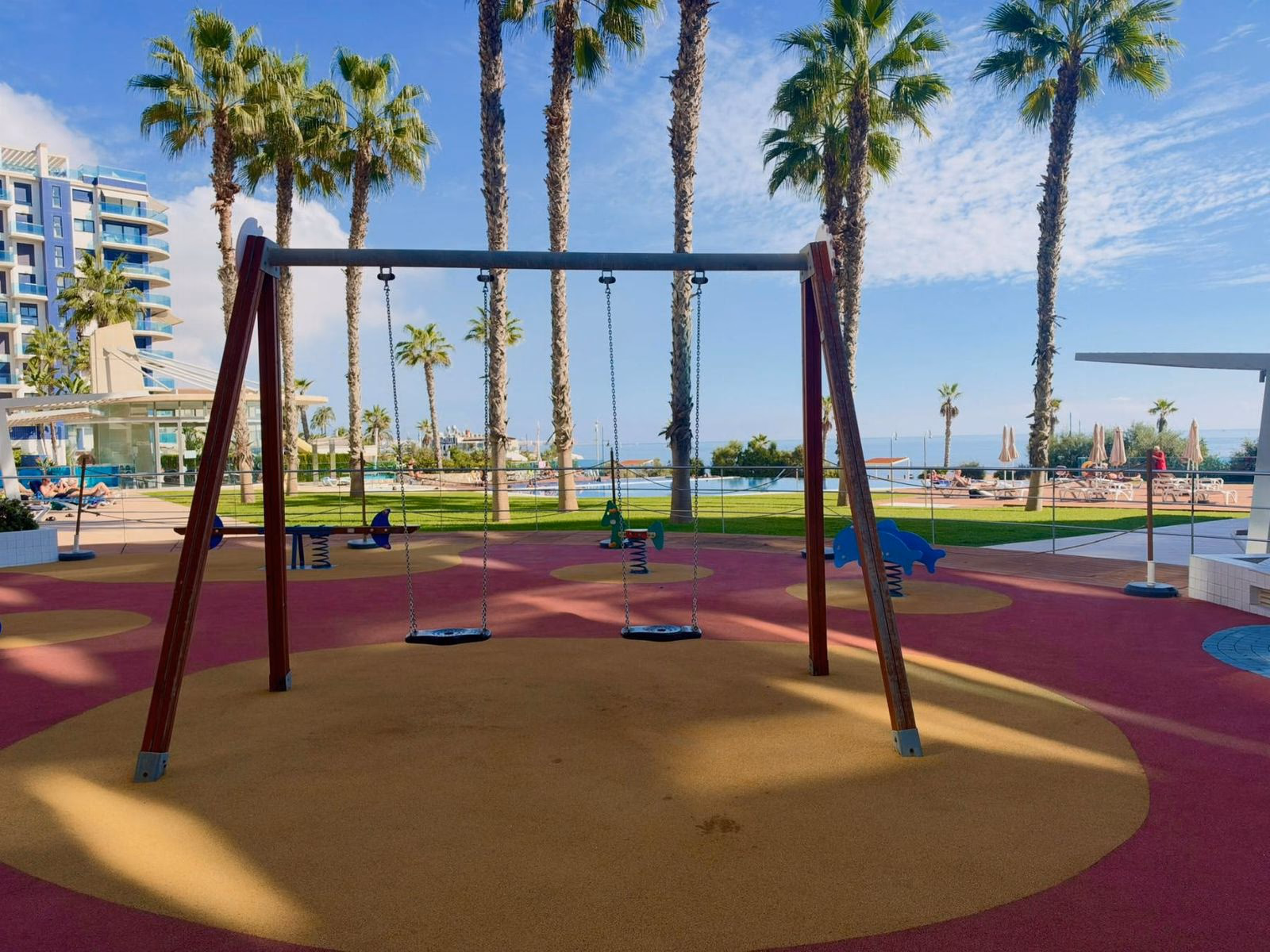 Zona infantil con columpios entre palmeras en los jardines de Sea Senses