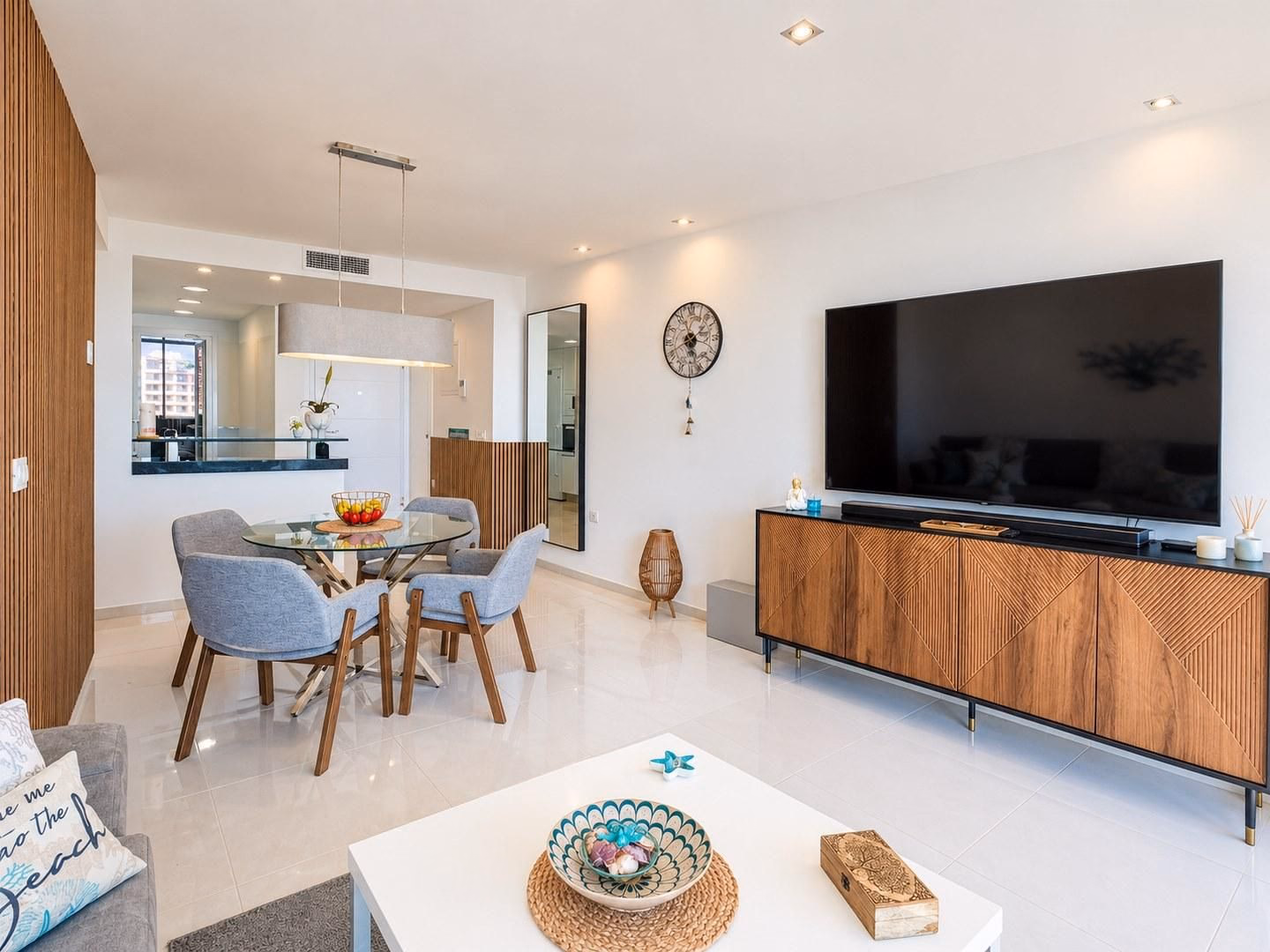Salón-comedor con la pared de la TV y la mesa de comedor junto al recibidor
