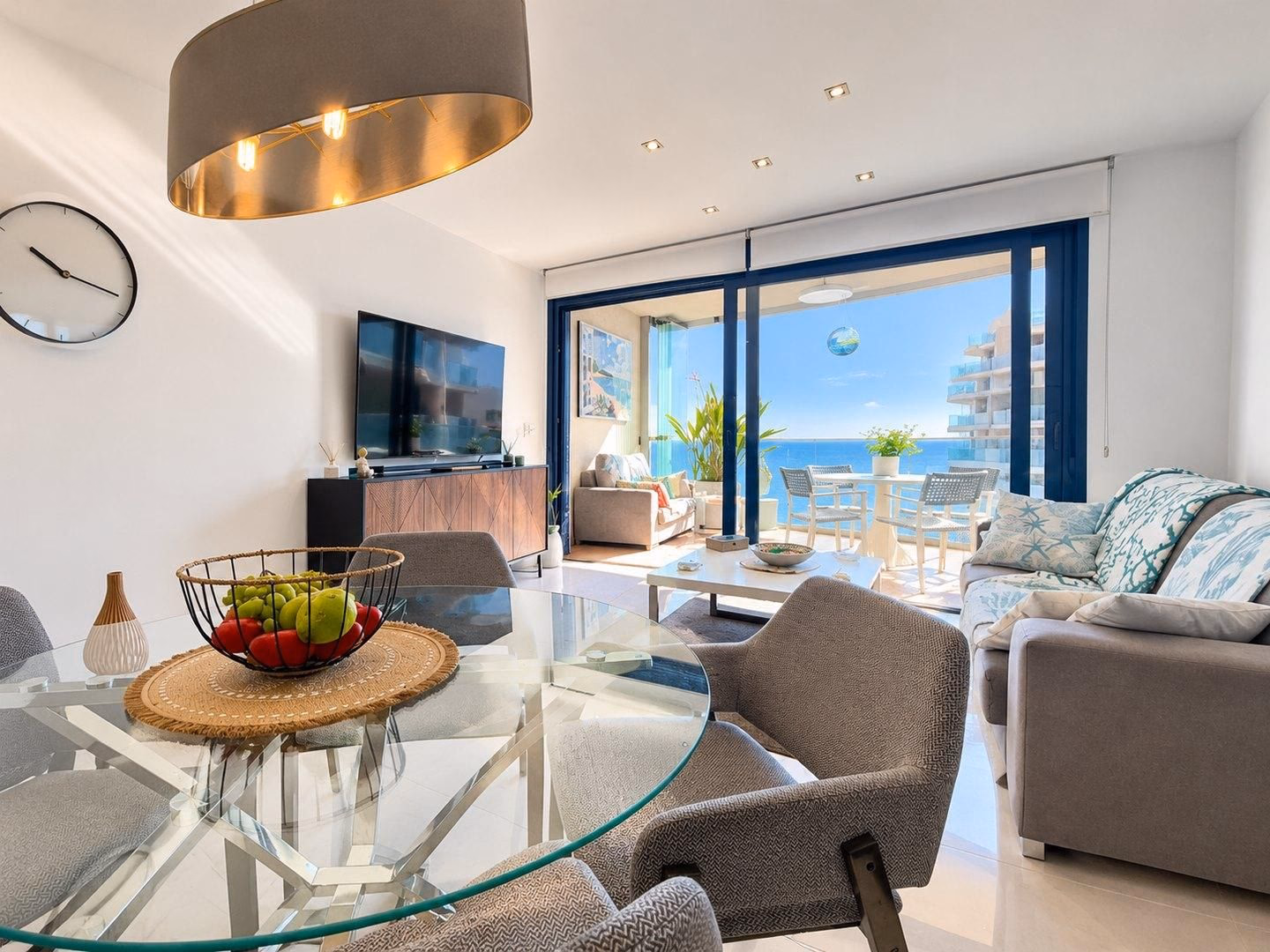Mesa de comedor de cristal delante del salón y la terraza con vistas al mar