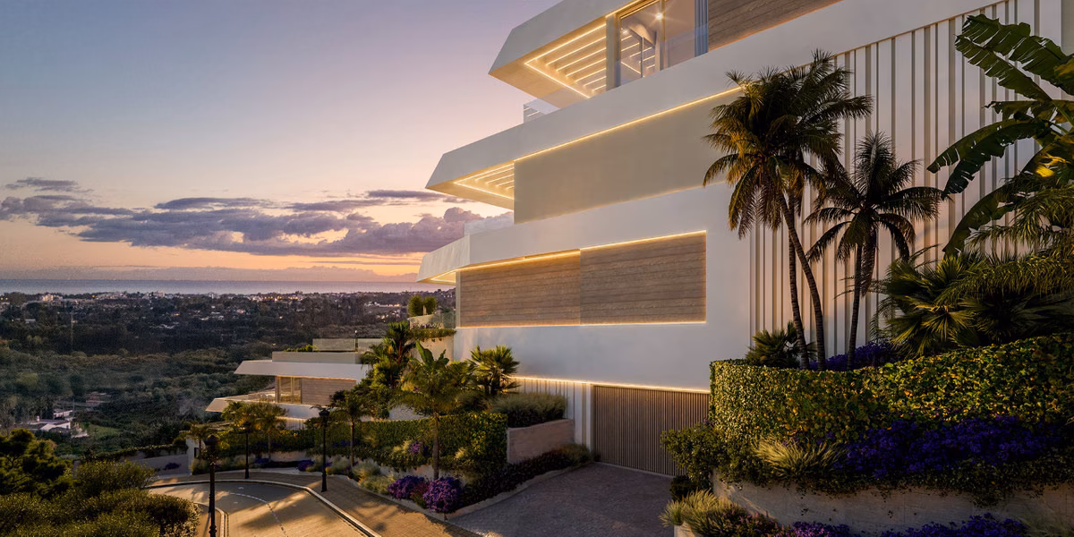Angle du bâtiment avec palmiers et terrasses au coucher du soleil, la côte au loin