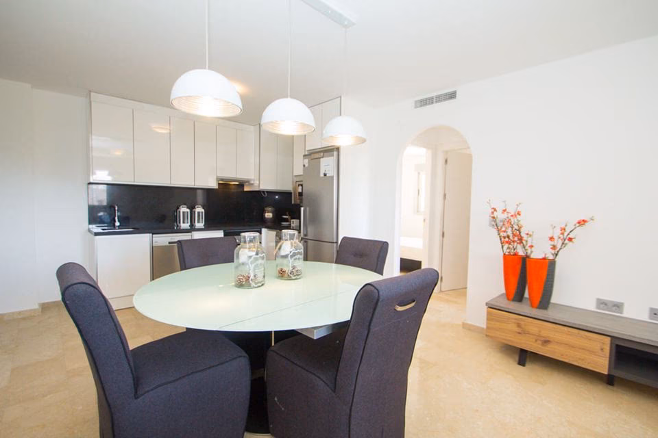 Dining area opening onto the white kitchen through an arched doorway