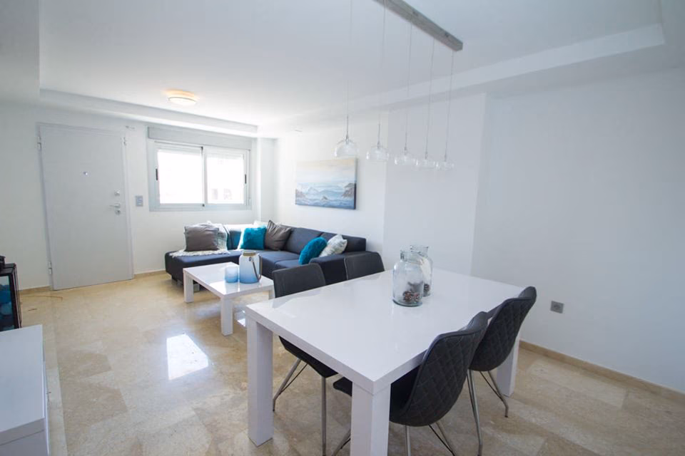 Open-plan living room with sofa, dining table and pendant lights