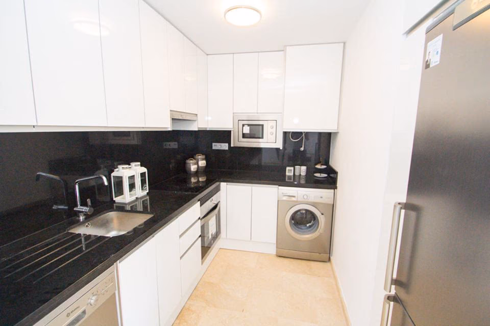 White kitchen with black worktop and washing machine