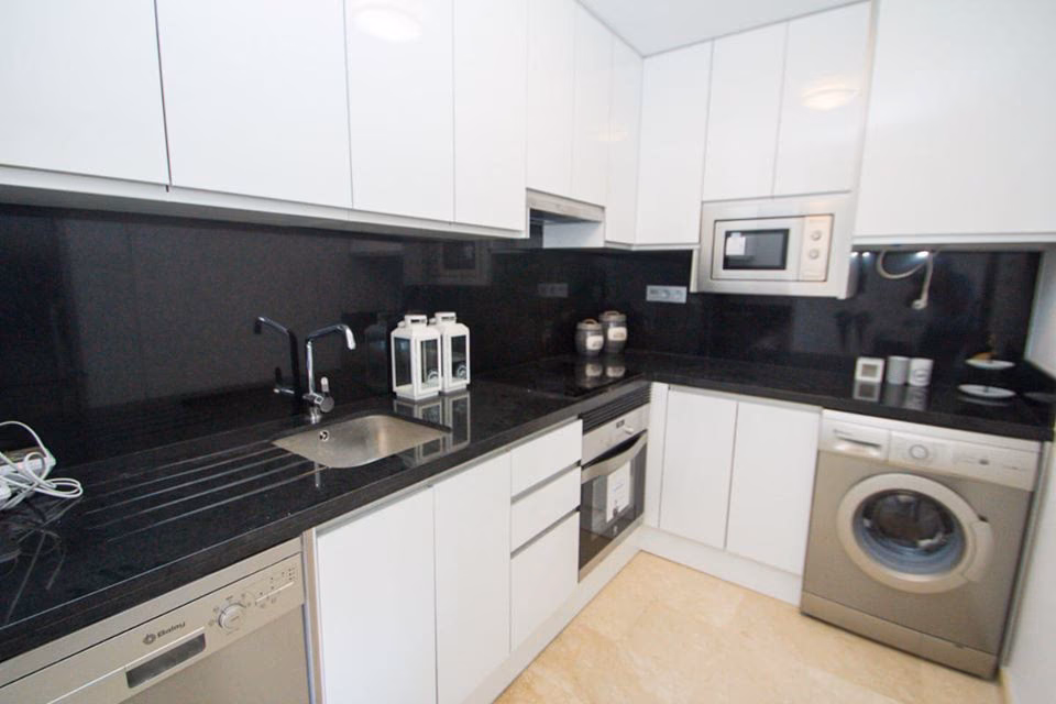 Kitchen with black splashback, oven and microwave
