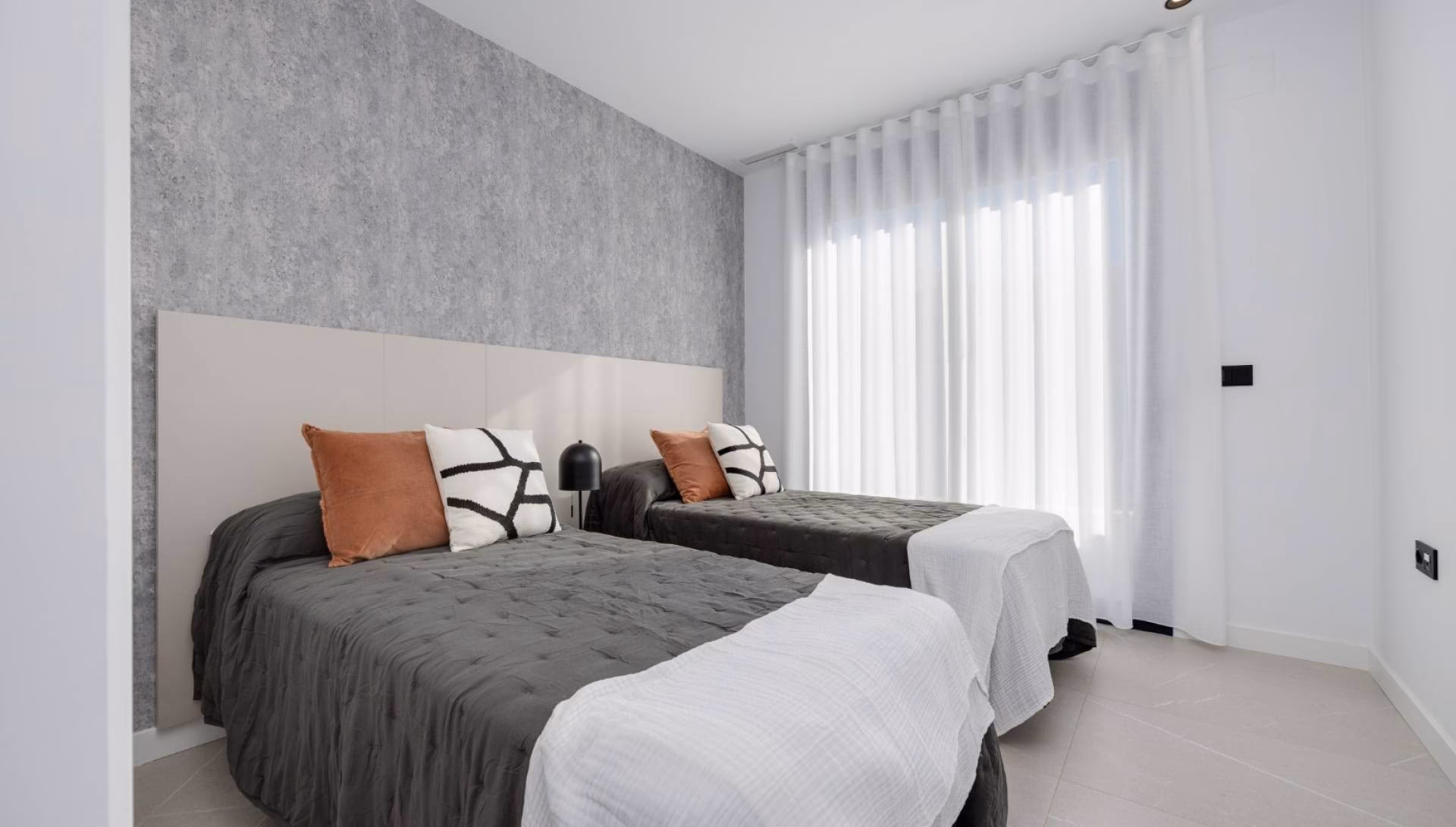 Schlafzimmer mit zwei Betten und grauer Akzentwand