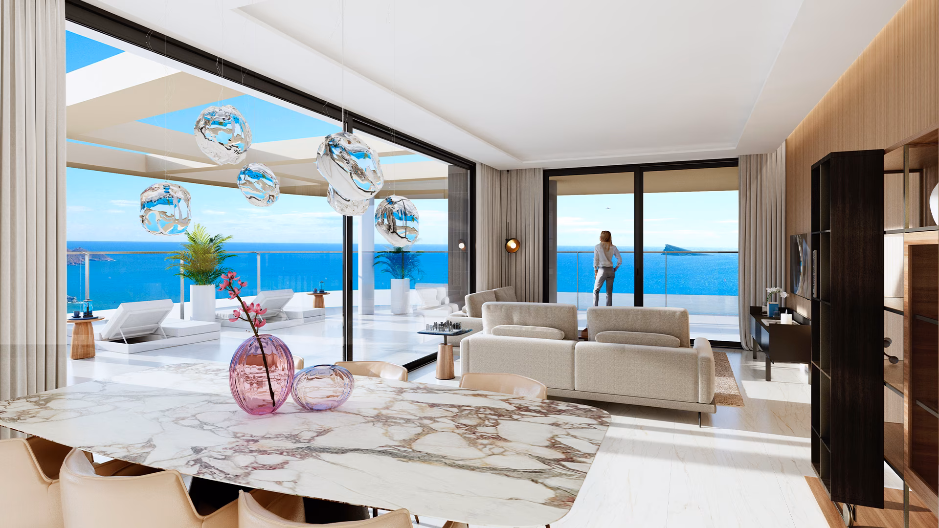 Living room with dining table and sea view through glass walls